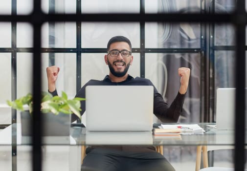 Business man sitting at his desk in the office with a laptop