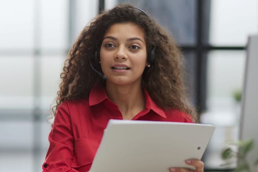 Attractive young business woman, writing notes to notebook at her workplace in office.