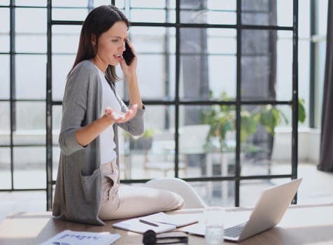 Businesswoman sitting in office, talking on the phone