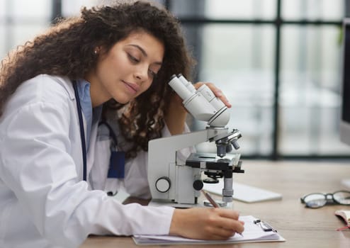 Attractive female scientist looking through a microscope