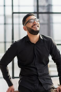 young businessman smiling in the office with his arms crossed