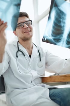 Male doctor in glass radiologist examines x-rays in a medical office.
