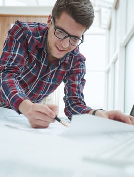 Close-up of engineer with pens over blueprints with sketches of projects
