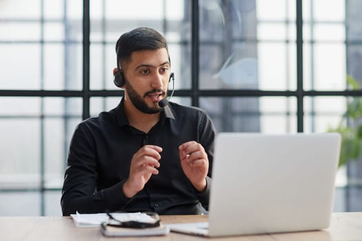 Positive businessman talking on headset at a computer
