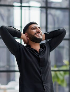 Portrait of relaxed businessman in modern office.Business young man relax after work of office window with business district view.
