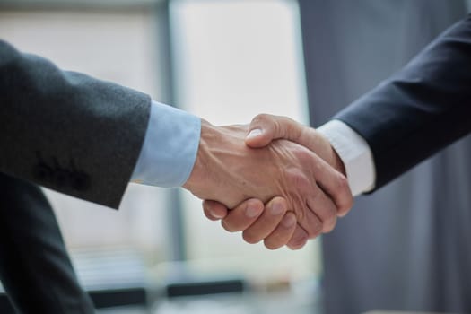 Two diverse professional business men executive leaders shaking hands at office meeting