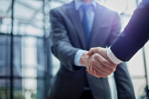 Two diverse professional business men executive leaders shaking hands at office meeting