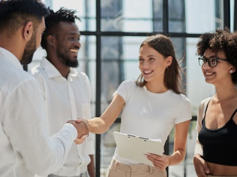 Glad to work with you. Young modern men in smart casual wear shaking hands and smiling while working in the creative office