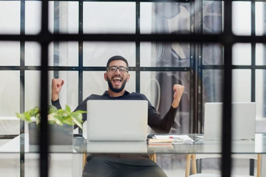 Business man sitting at his desk in the office with a laptop