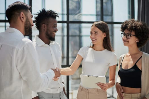 Glad to work with you. Young modern men in smart casual wear shaking hands and smiling while working in the creative office