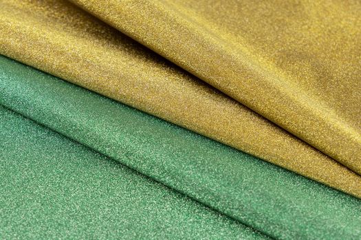 Golden and green wave shiny glitter paper texture. Shining luxurious fabric. Glimmering light green golden color, christmas background