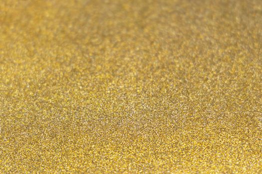 Golden shiny glitter paper texture. Shining luxurious fabric. Glimmering golden christmas background