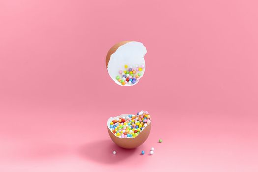 Broken decorative easter egg with colorful confetti. Minimal composition, vivid color pastel pink background. Copy space.