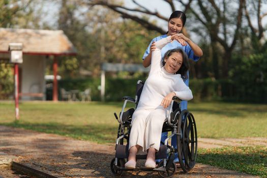 Elderly asian senior woman on wheelchair with nurse. Nursing home hospital garden concept.