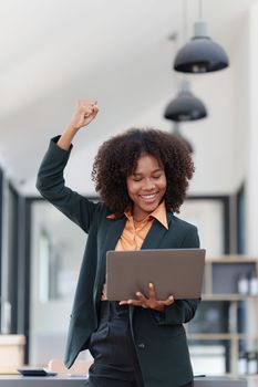 Beautiful American African business women with hands up in winner gesture. Happy to be successful celebrating achievement and success concept.