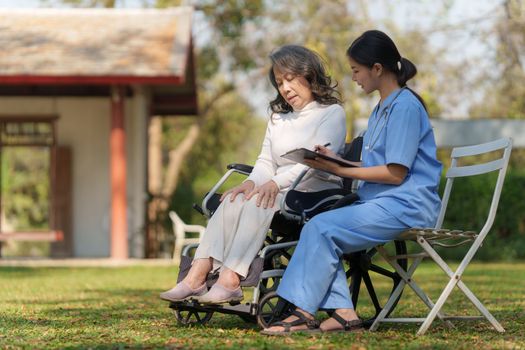 Elderly asian senior woman on wheelchair with nurse. Nursing home hospital garden concept.