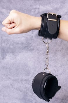 Hand with scars and handcuffs on a gray background