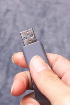 USB flash drive in hand on a gray background