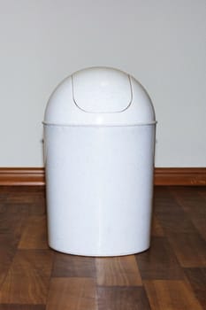 Waste bin on a wooden floor against wall background