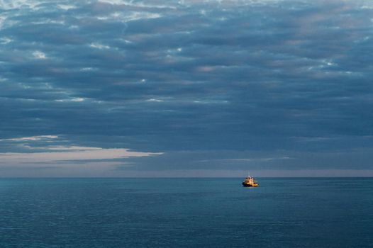 a small ship at sea against the sunset sky.