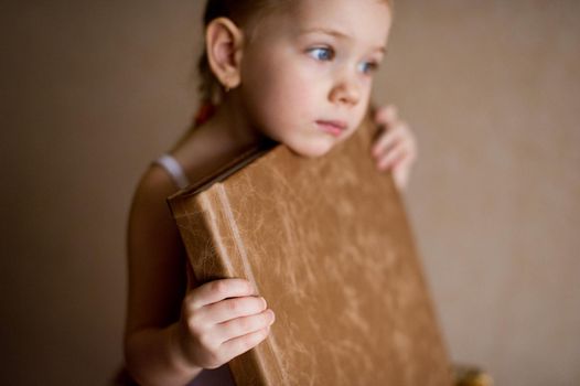 a little girl is holding a photo book in natural brown leather