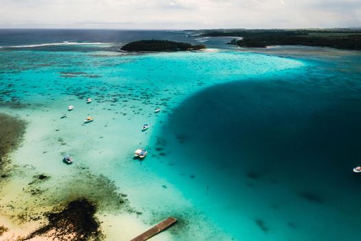 Aerial picture of the east coast of Mauritius Island. Beautiful lagoon of Mauritius Island shot from above. Boat sailing in turquoise lagoon.