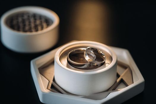 two gold wedding rings in a white box on a black background.