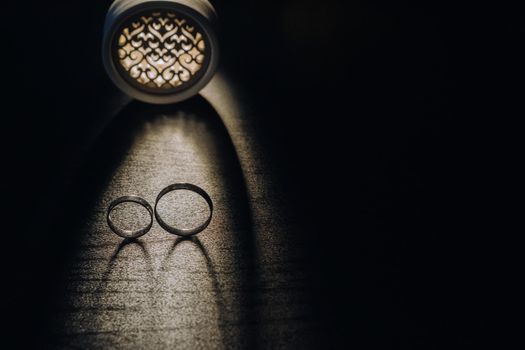 Close-up of two gold wedding rings on a black background.