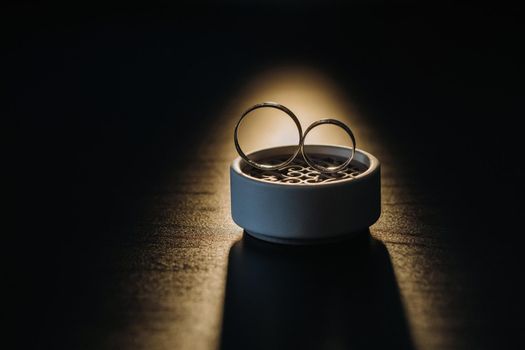 two gold wedding rings in a white box on a black background.