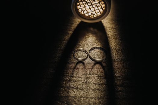 Close-up of two gold wedding rings on a black background.