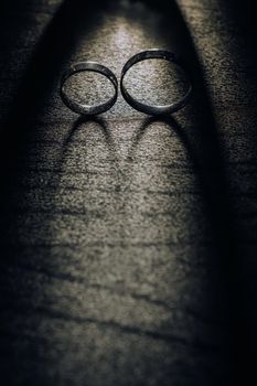 Close-up of two gold wedding rings on a black background.