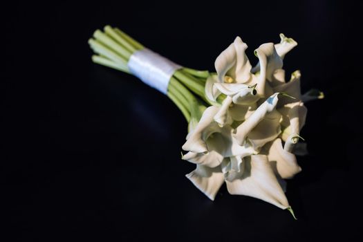 Wedding bouquet of white Calla lilies on a black background.