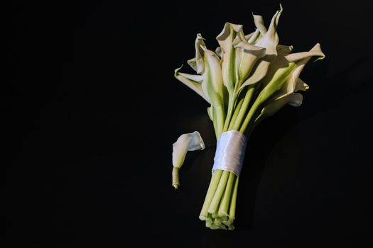 Wedding bouquet of white Calla lilies on a black background.