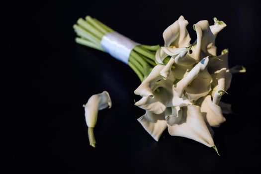 Wedding bouquet of white Calla lilies on a black background.