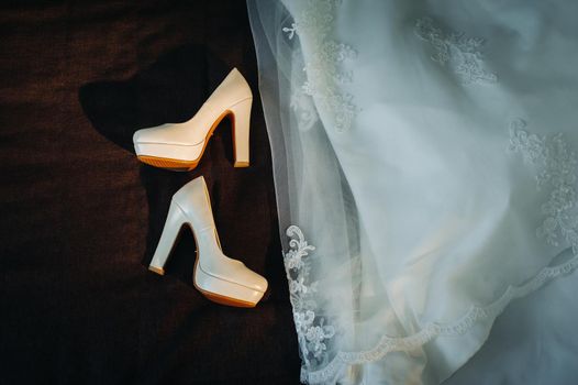 white wedding shoes and dress on black background.