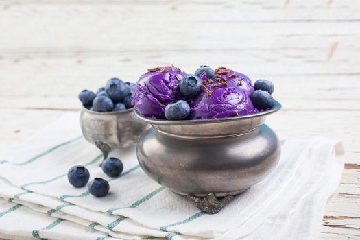 Fresh blueberry ice cream inside a pewter cup on old white wooden table