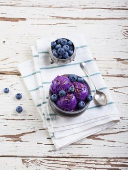 Fresh blueberry ice cream inside a pewter cup on old white wooden table