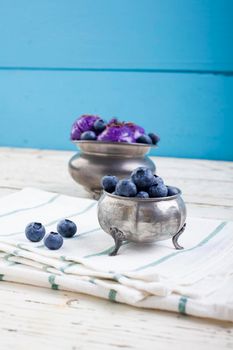 Fresh blueberry ice cream inside a pewter cup on old white wooden table