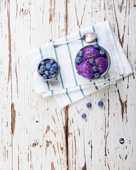 Fresh blueberry ice cream inside a pewter cup on old white wooden table