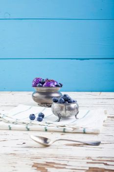 Fresh blueberry ice cream inside a pewter cup on old white wooden table