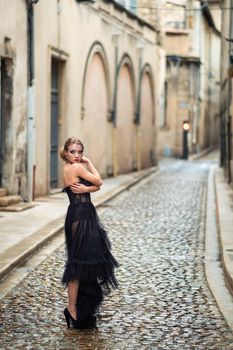 A stylish bride in a black wedding dress in the ancient French city of Avignon. A model in a black dress.