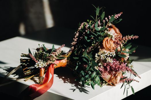 wedding bouquet with roses on the table and a boutonniere.The decor at the wedding.