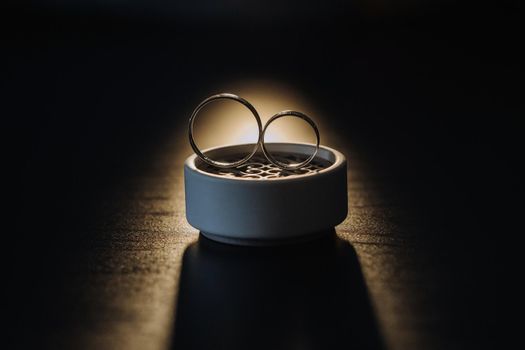 two gold wedding rings in a white box on a black background.