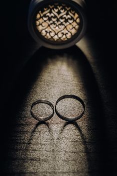 Close-up of two gold wedding rings on a black background.