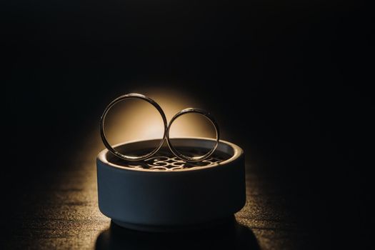 two gold wedding rings in a white box on a black background.