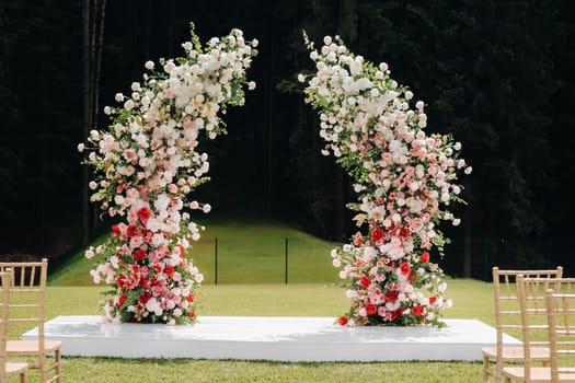 Wedding ceremony on the street on the green lawn.Decor with fresh flowers arches for the ceremony.