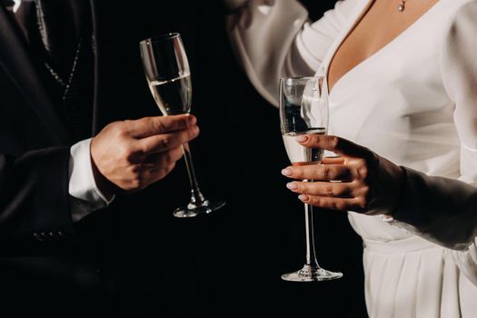 A man and a woman hold champagne glasses in their hands close-up.