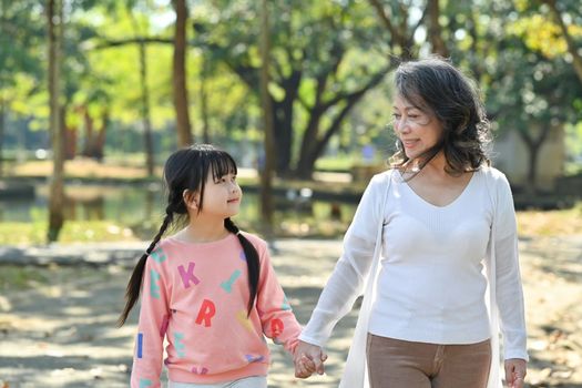 Loving middle aged woman and little granddaughter enjoying leisure weekend time at outdoor surrounded by nature view.