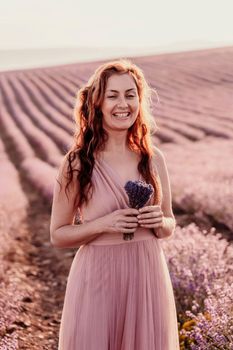 Woman lavender field sunset. Romantic woman walks through the lavender fields. illuminated by sunset sunlight. She is wearing a pink dress with