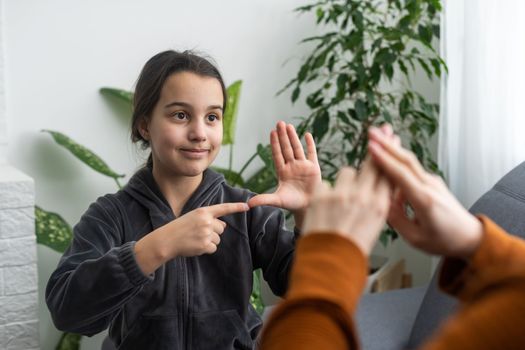 Small Caucasian teen girl child do articulation exercises with caring mother or teacher at home. Little kid pronounce sounds speak talk with tutor or coach, engaged in voice pronunciation together.